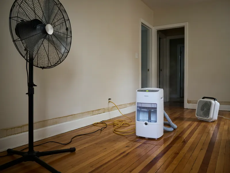 Fans and a dehumidifier drying out a room after a leak